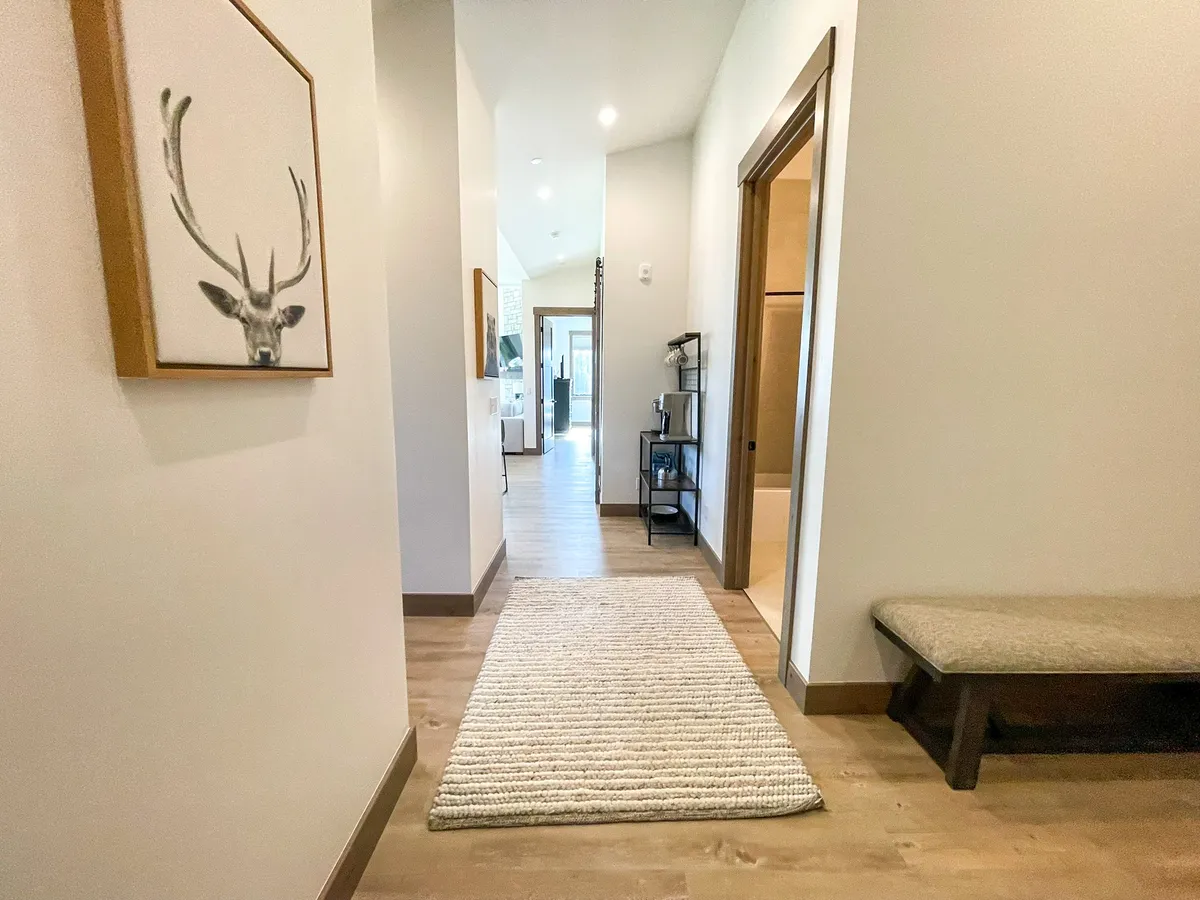 A welcoming entry area with a wooden bench, woven rug, and framed deer artwork. The space is cozy and inviting, perfect for transitioning from outdoor activities to indoor relaxation, as described in the section.