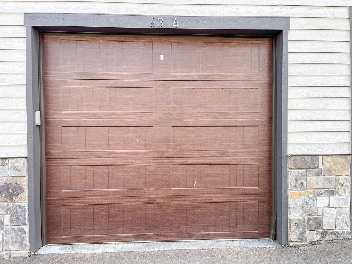 This image clearly showcases a garage door with attractive stonework and an address number, focusing on the garage's exterior. It visually supports the section's mention of secure private parking and gear storage, making the connection between the home and adventure equipment.